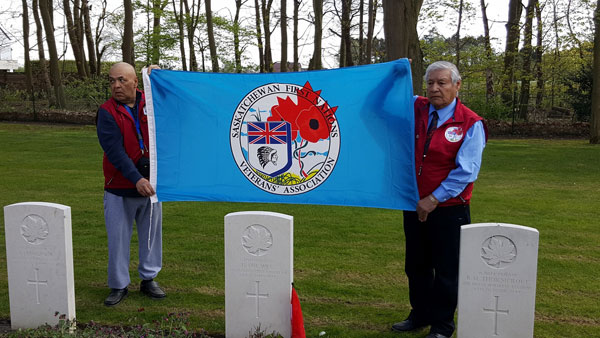Barry Brass on left and SFNVA Grand Chief Steven Ross hold the Associations flag during the ceremony to honour Sargent Harvey Dreaver from Mistawasis First Nation. 